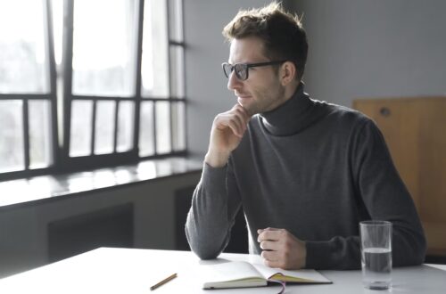 man in an office wearing glasses looking away in thought